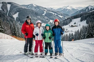 Famille en tenue de ski au sommet d'une piste du Jura avec vue sur les forêts enneigées et un chalet en vallée