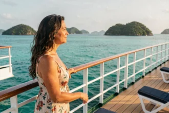Femme en robe fleurie admirant la vue depuis le pont d'un bateau de croisière aux Caraïbes