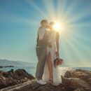 a man and woman kissing on a rocky beach