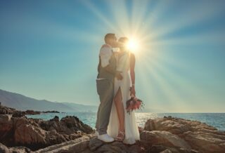 a man and woman kissing on a rocky beach