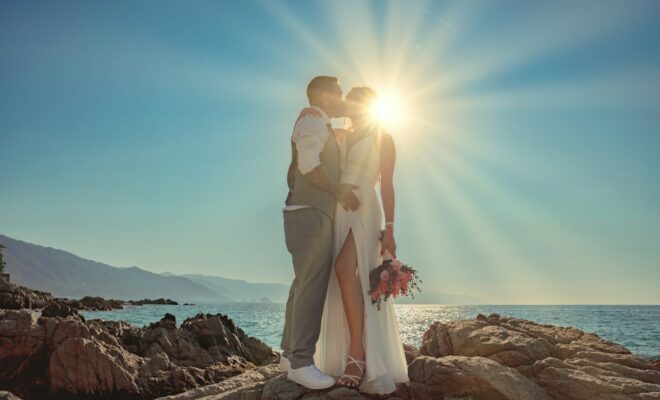 a man and woman kissing on a rocky beach