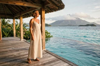 Femme en robe de lin sur la terrasse d'un bungalow sur l'eau dans un hôtel de luxe en Guadeloupe
