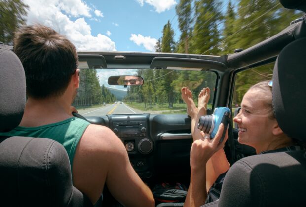 Young woman with instant camera driving on road trip with boyfriend, Breckenridge, Colorado, USA